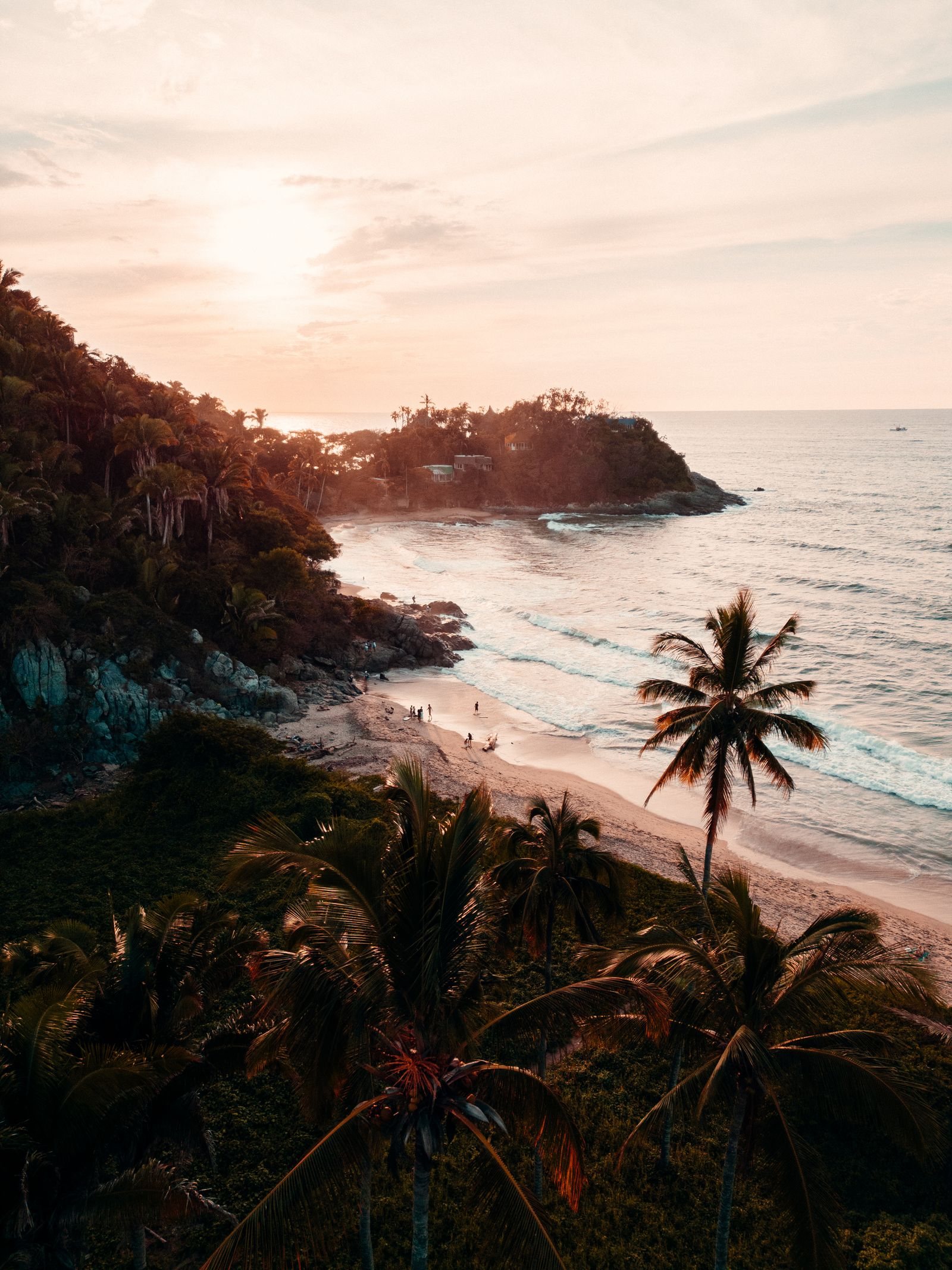 Vista aérea al atardecer de la costa de San Francisco, Nayarit, con palmeras, rocas y una pequeña playa