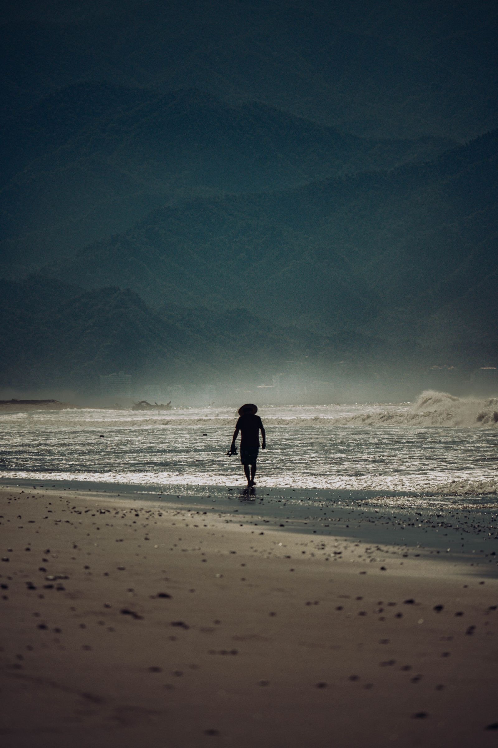Persona caminando sola por la orilla de la playa de Nuevo Vallarta con montañas entre la bruma