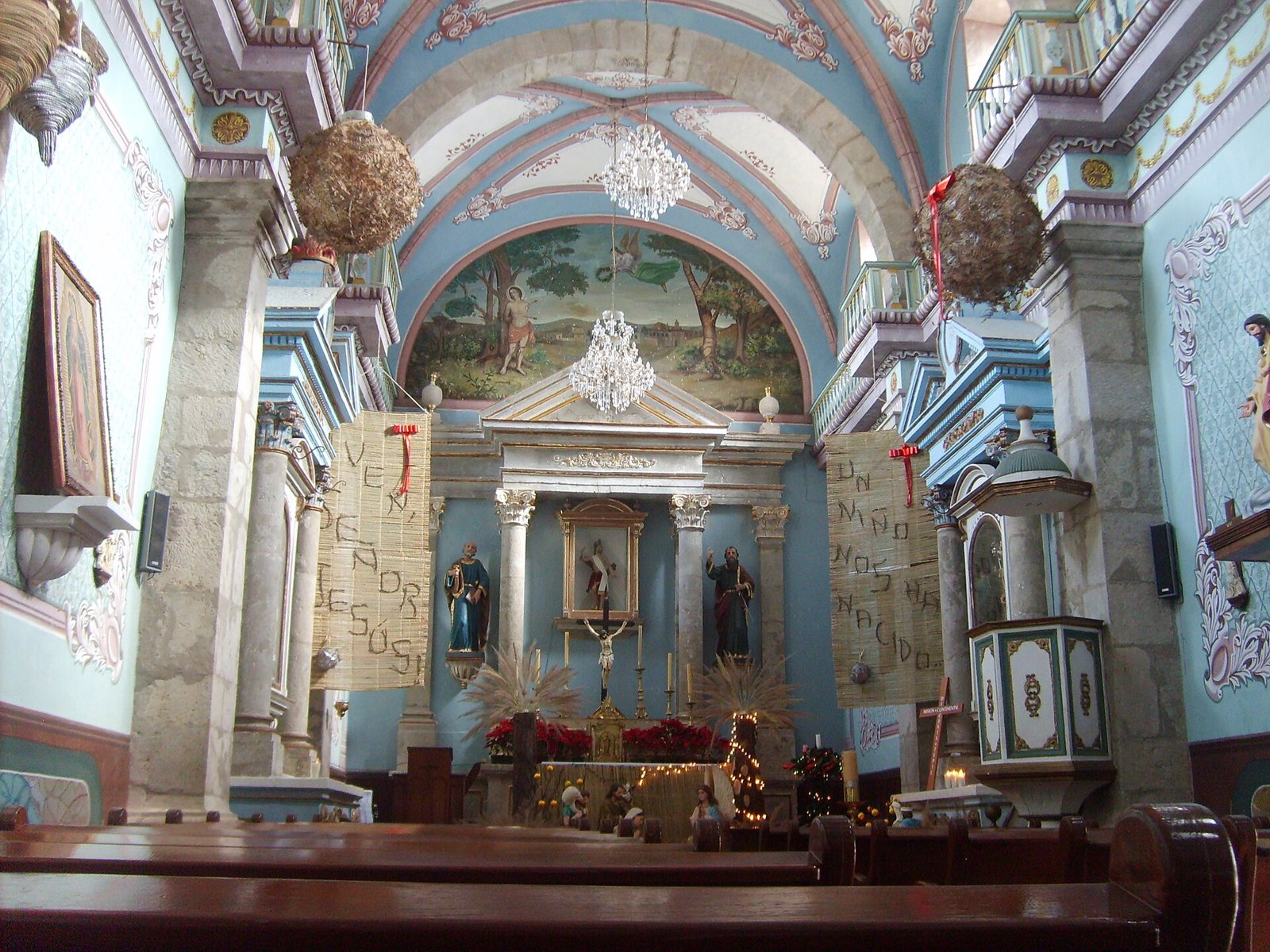 Interior del templo de San Sebastián con bóveda pintada, candiles y retablo principal