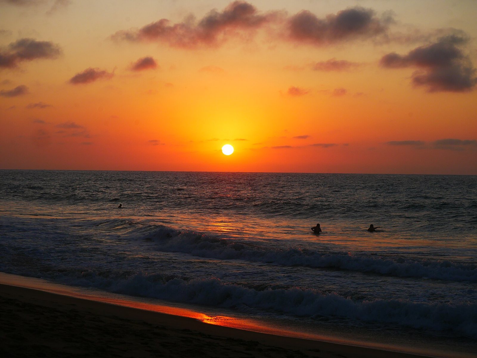 Atardecer naranja sobre el mar en la playa de San Pancho, con el sol a punto de ocultarse en el horizonte