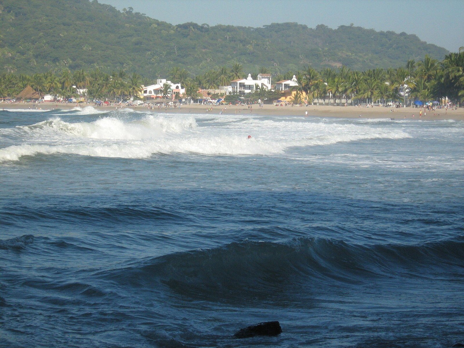 Oleaje en la bahía de Lo de Marcos con el pueblo y los cerros verdes al fondo