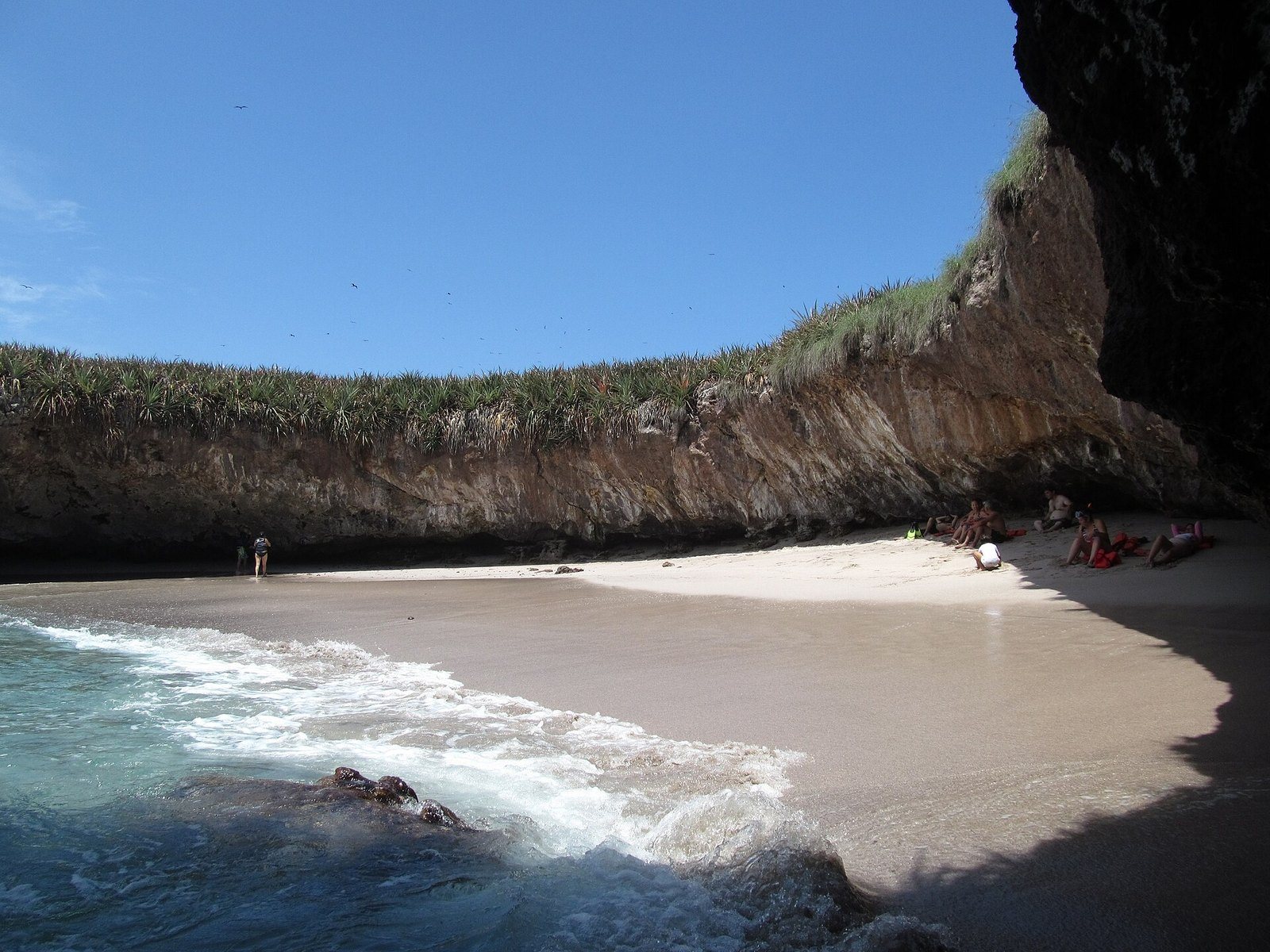 Playa Escondida vista desde el agua, rodeada por paredes de roca con vegetación