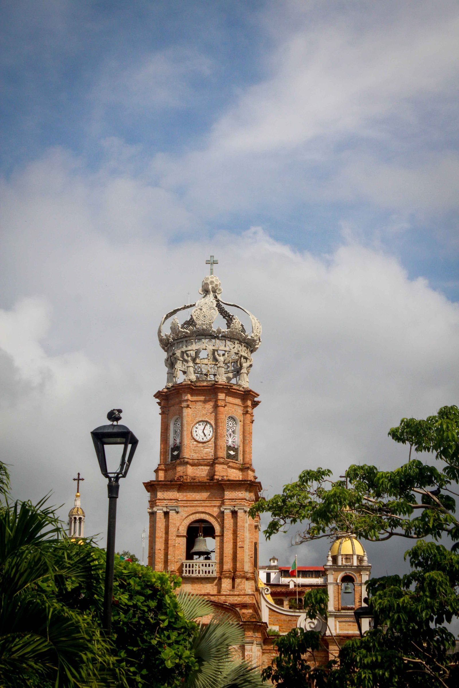 Torre de ladrillo con reloj y corona blanca de la parroquia de Guadalupe en Puerto Vallarta