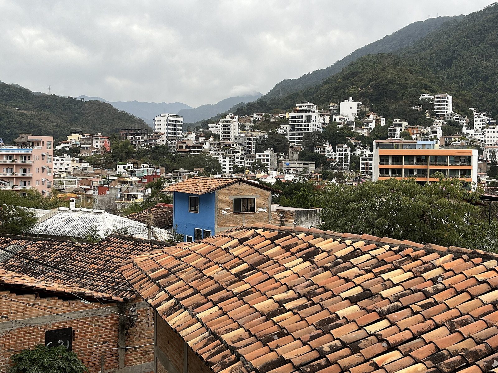 Techos de teja y casas en las laderas del centro de Puerto Vallarta con la sierra al fondo