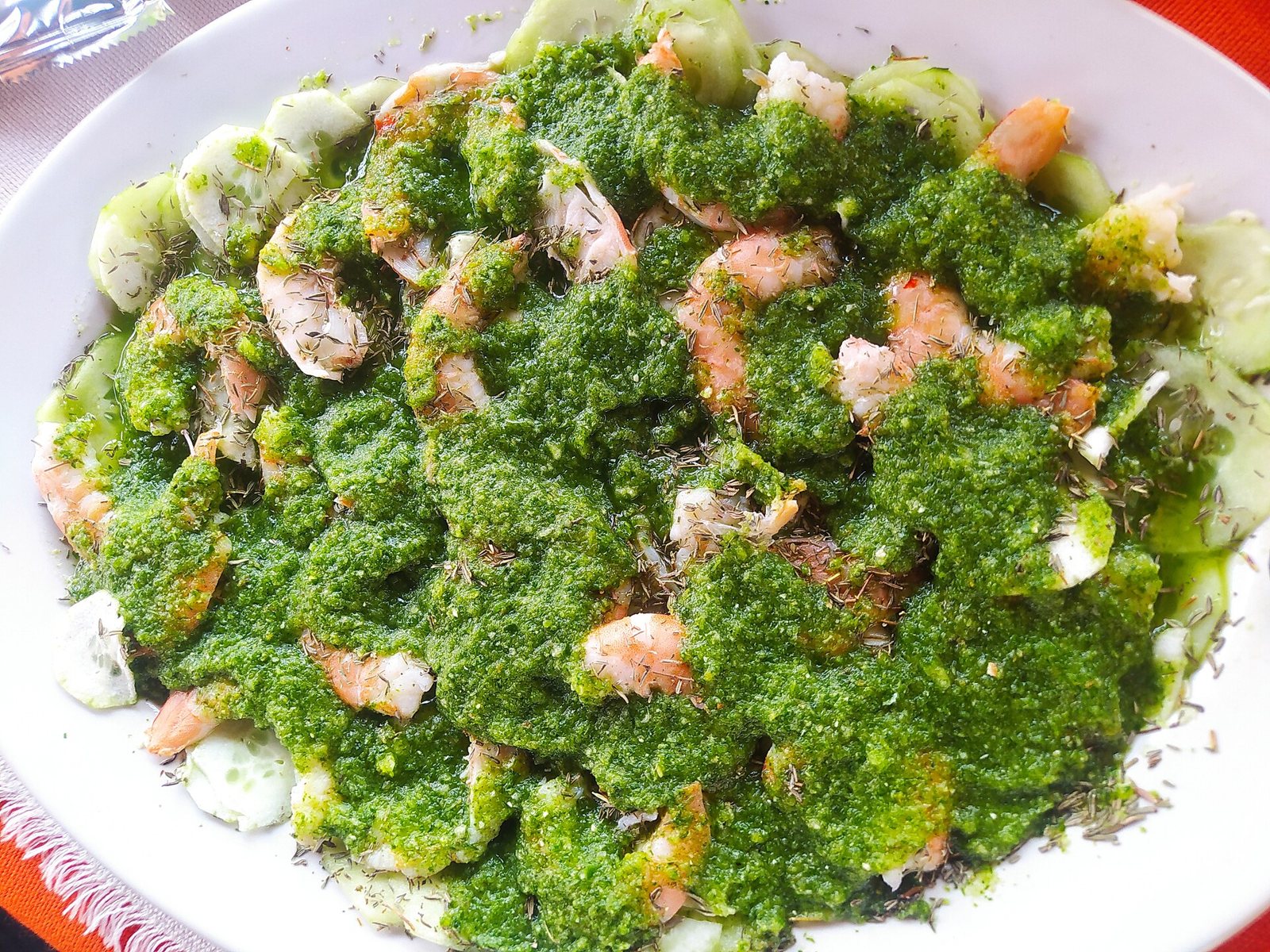 Plato de aguachile verde con camarones crudos cubiertos de salsa de chile verde sobre rodajas de pepino