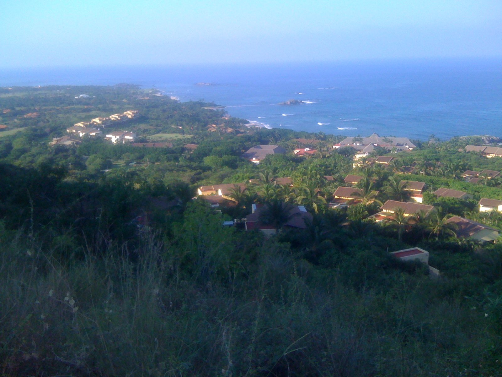 Villas con techos de teja entre palmeras en la península de Punta Mita, con el mar azul y pequeños islotes al fondo